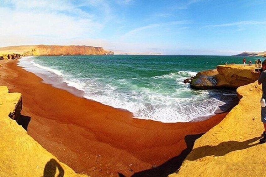 Una playa de arena rojiza, olas del océano y acantilados rocosos. 1