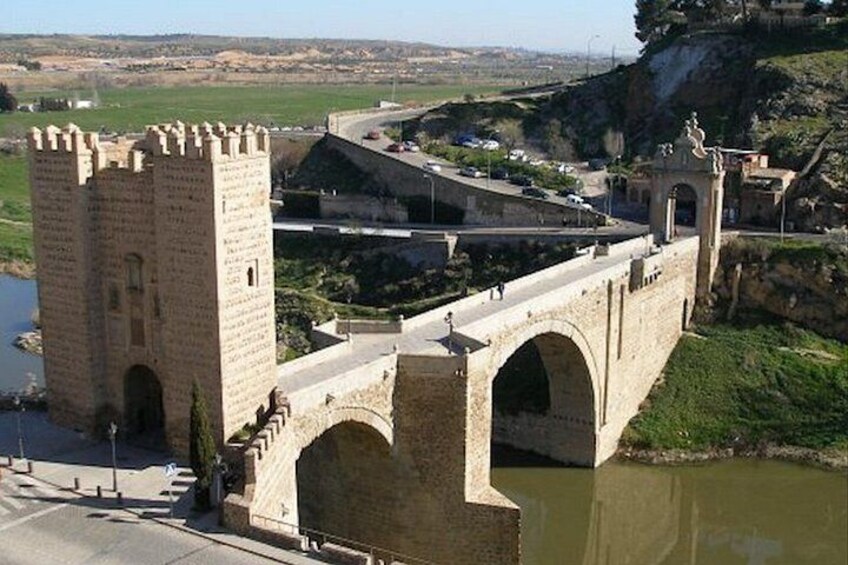 Un puente de piedra con arcos, una torre y un río. 2
