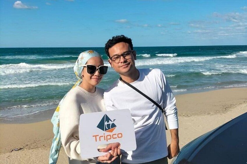 A beach with waves, a car, and a Tripco sign. 2