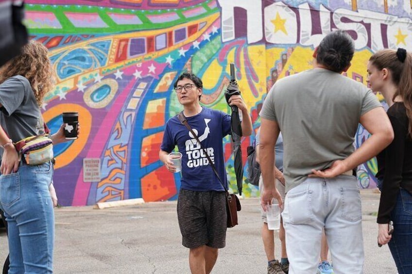 Un grupo de personas frente a un colorido mural con la palabra "HOUSTON" a la vista. 1