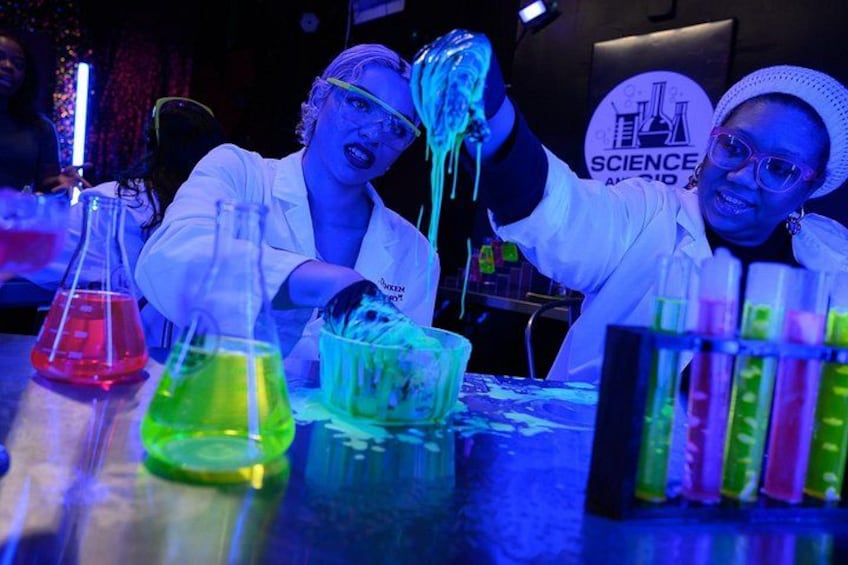 Two people in lab coats working with colorful liquids in beakers. 3
