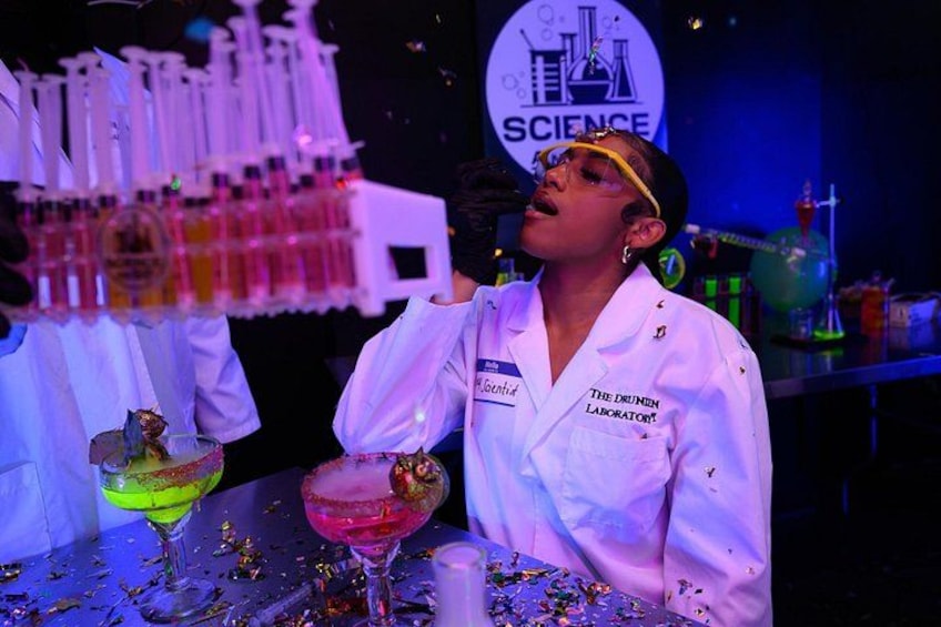 A person in a white lab coat with 'The Drunen Laboratory' text, holding a microphone. 1