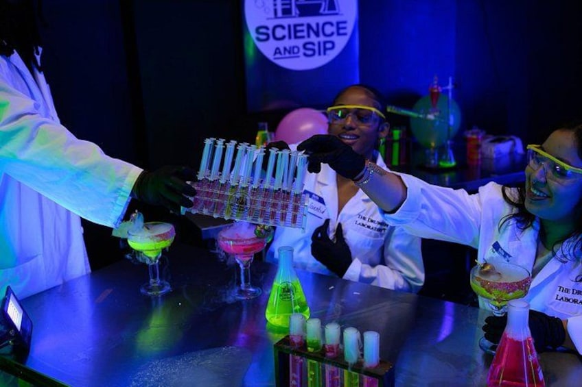 A science-themed bar with people in lab coats, test tubes, and colorful drinks. 2