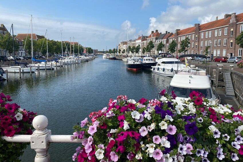 A canal with boats, a row of houses, and a flower-lined railing. 5