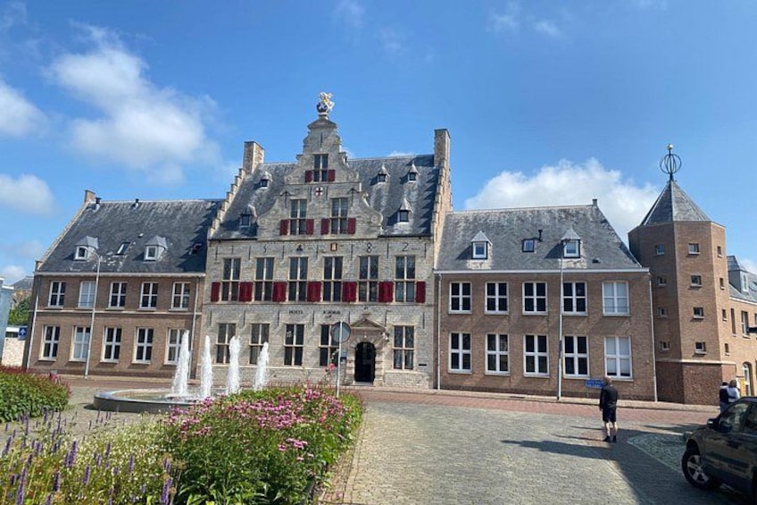 A historic building with a fountain in front, surrounded by flowers. 2