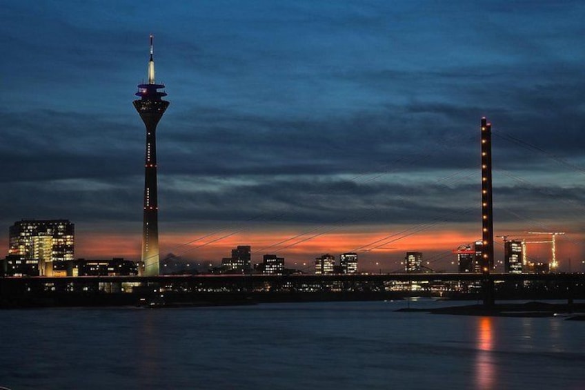 Een stadszicht in de schemering met verlichte gebouwen en twee opvallende torens. 1