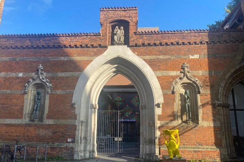 Un edificio de ladrillo con un amplio arco de entrada, una estatua y una bicicleta. 5
