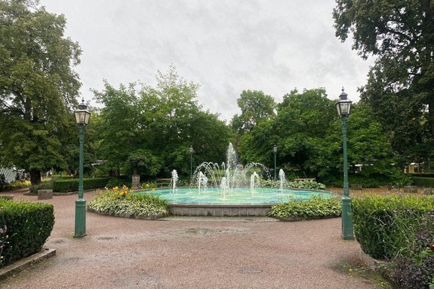 En fontän omgiven av grönska och lyktstolpar i en park. 3