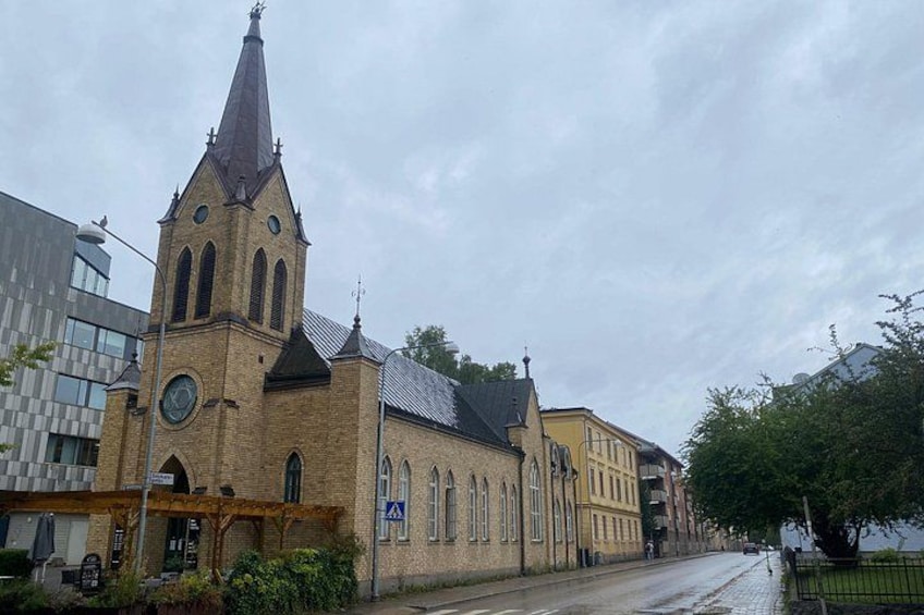 En kyrka med ett högt torn, en klocka och en fasad av tegel. 2