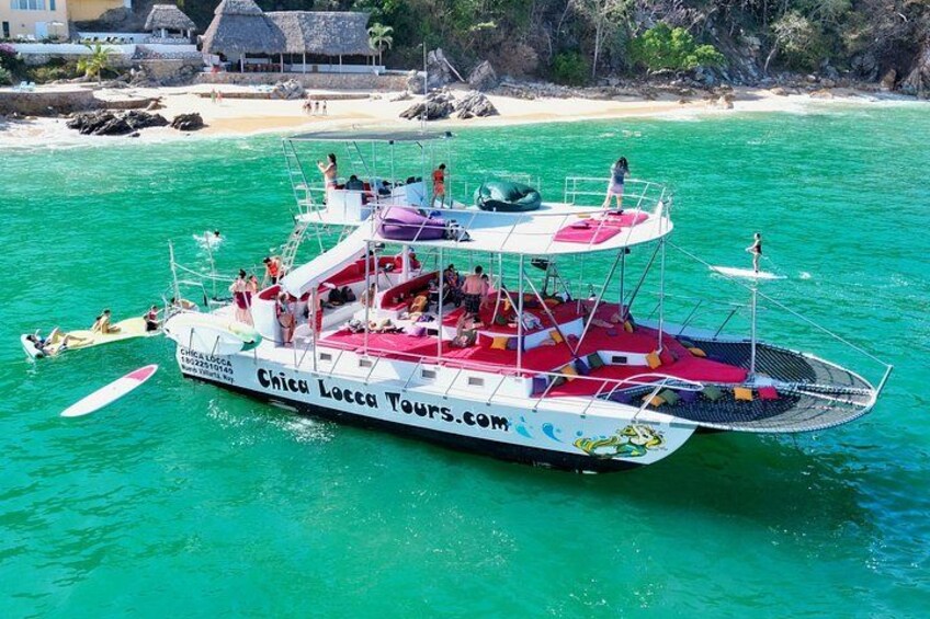 A boat named Chicu Lacca Tours.com on turquoise waters with a beach and rocky outcrops in the background. 4