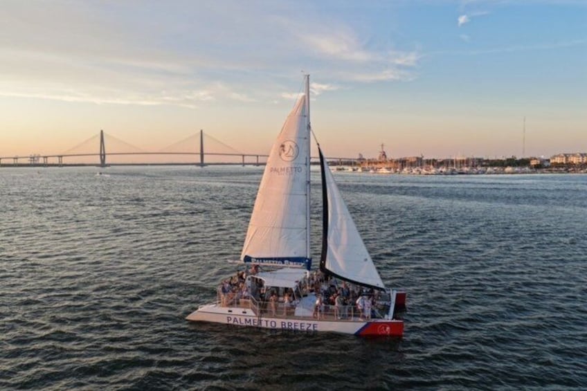 A sailboat named 'Palmetto Breeze' on the water with a bridge in the background. 4