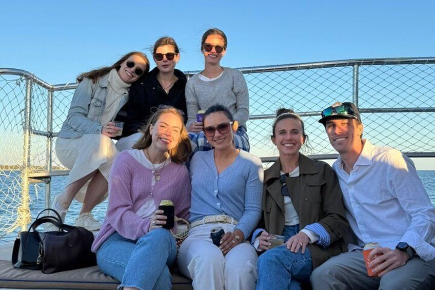 A group of people on a boat with a metal railing and water in the background. 4