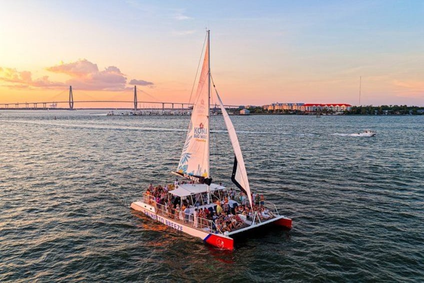 Un velero con una multitud a bordo navegando en un cuerpo de agua, con un puente al fondo. 1