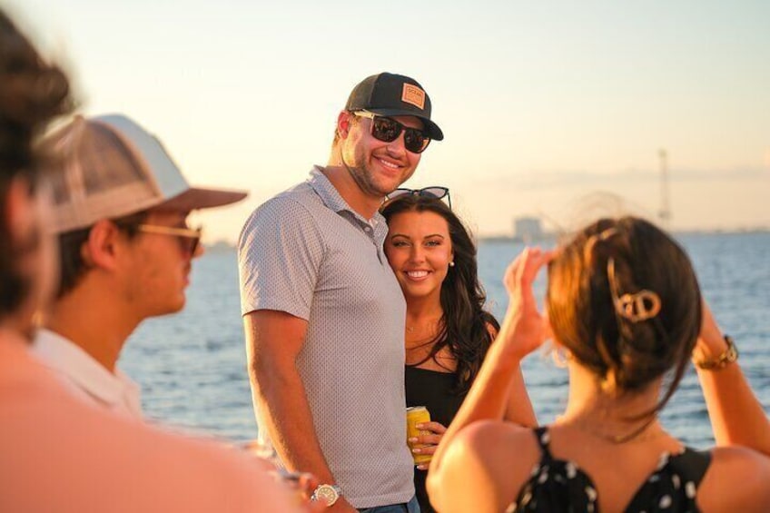 A group of people on a boat at sunset with a bridge in the background. 5