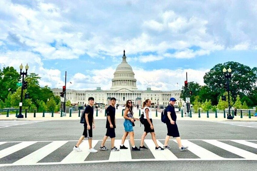 En gruppe mennesker krydser en gade med bygningen U.S. Capitol i baggrunden. 1
