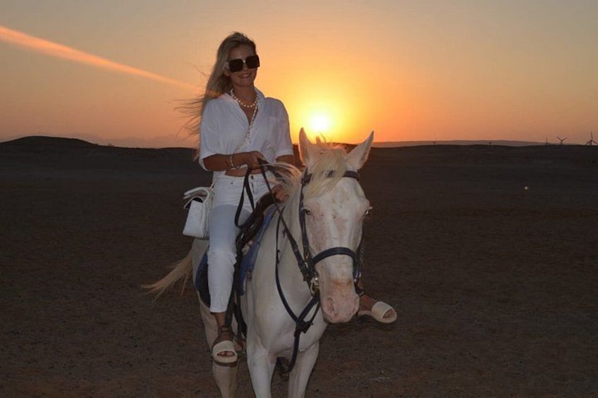 Una persona cavalca un cavallo in un paesaggio desertico al tramonto. 3