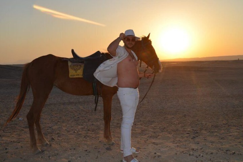 A person with a horse in a desert landscape at sunset. 5