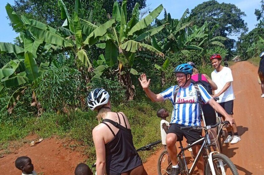 A person on a bicycle with a blue and white jersey, another person on a bicycle, and a child standing nearby. 3