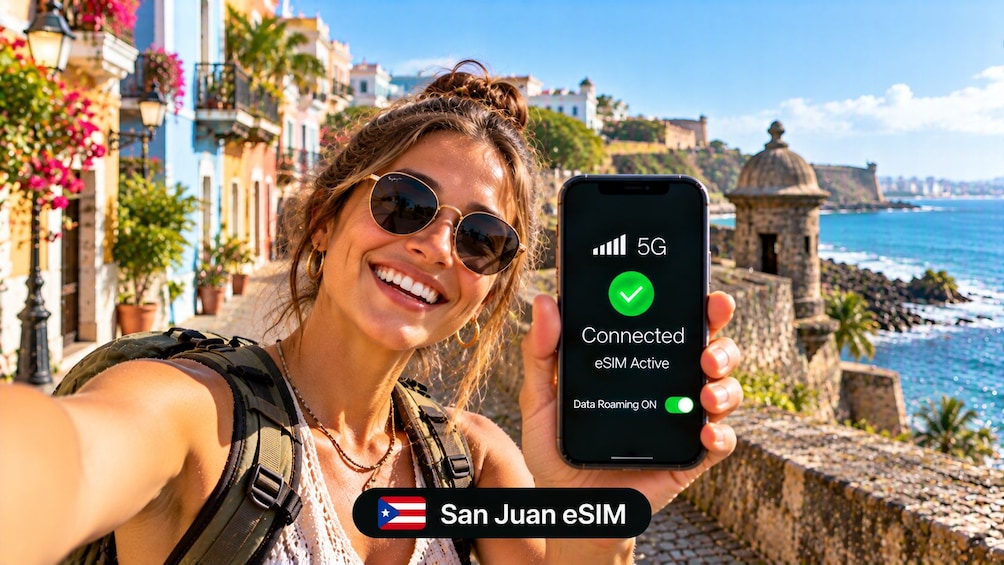 A person holding a smartphone displaying a 5G connection status with a coastal cityscape in the background. 2