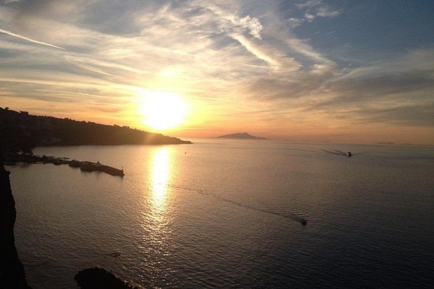 A sunset over a calm sea with a silhouette of a coastline and a distant island. 3