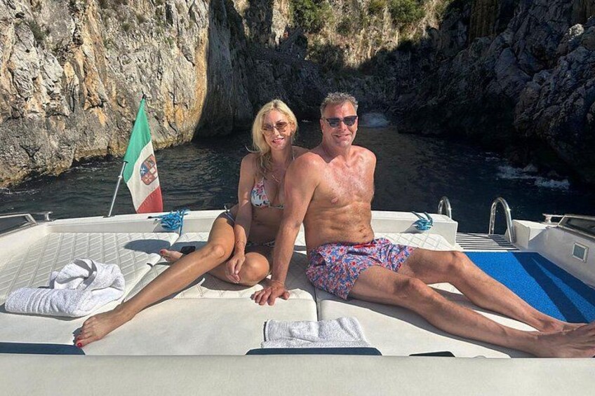 A boat with two people, a flag, and rocky cliffs in the background. 4