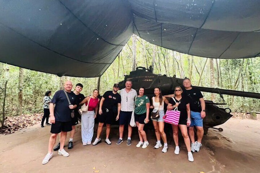 Un grupo de personas posando frente a un helicóptero militar en una zona boscosa. 2