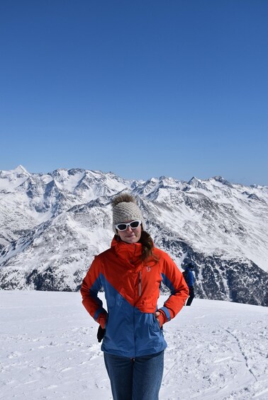 A person standing on a snowy mountain with a clear blue sky in the background. 5