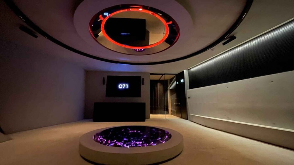 A modern interior with a circular seating area, a wall-mounted TV, and a digital display showing '071'. 3