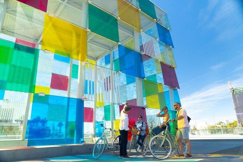 A colorful glass building with people and bicycles. 2