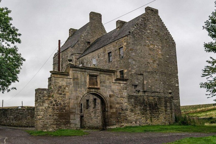 Un bâtiment en pierre doté d’une grande entrée en arc de cercle, entouré de pelouse et d’un mur de pierre. 5