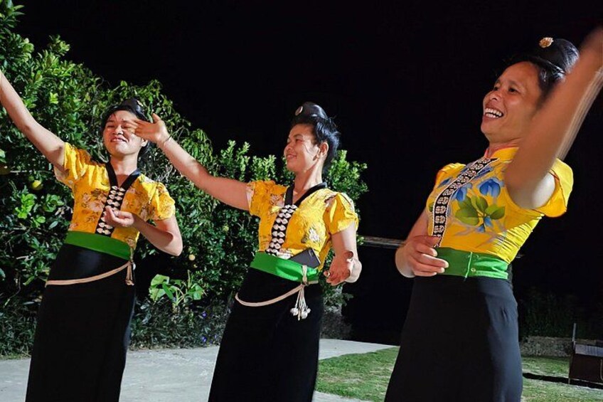 Three individuals performing a dance in traditional attire with a dark background. 3
