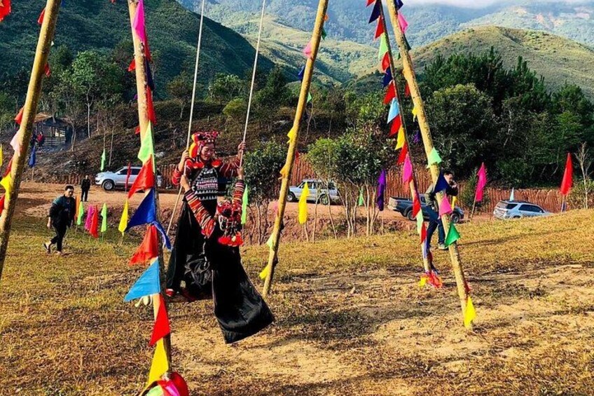 A person on a swing decorated with colorful flags, with a mountainous landscape in the background. 4