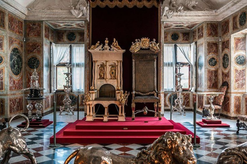 Ein prächtiger Raum mit einem goldenen Thron in der Mitte, einem roten Teppich und dekorativen Skulpturen. 4