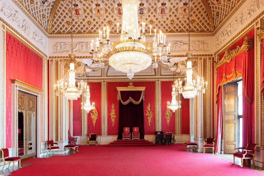 A grand hall with red carpet, ornate chandeliers, and gold accents. 3