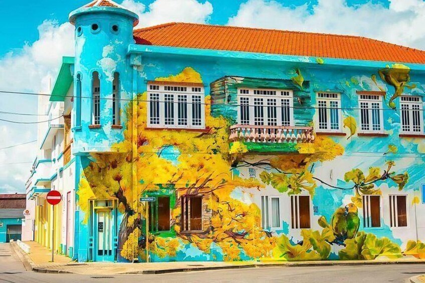The mural at Fleur de Marie features vibrant street art with colorful images that reflect the local culture and history of Willemstad. 5