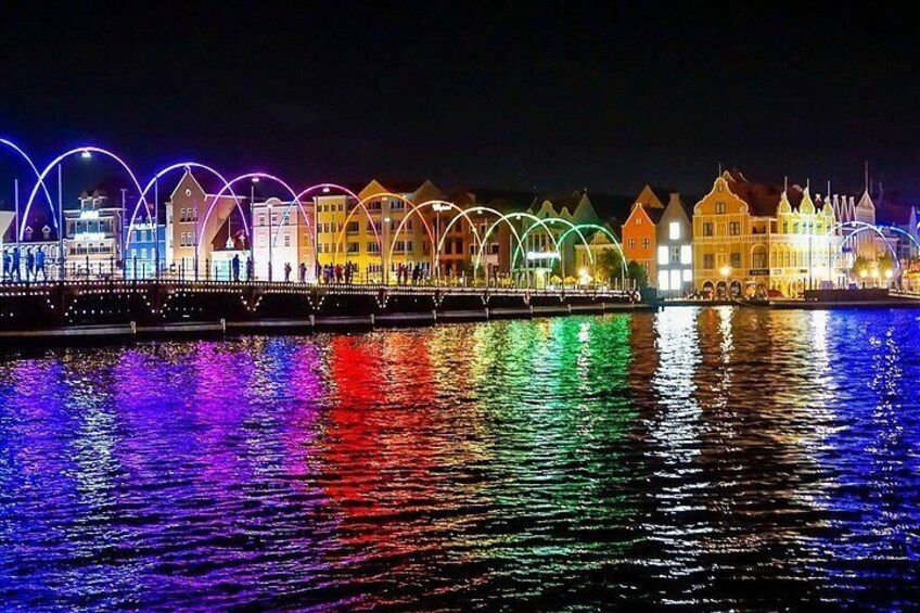 The Pontoon Bridge at night is atmospherically lit, with warm lights reflecting in the dark water of St. Anna Bay. A romantic and iconic view in Willemstad. 2