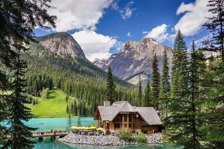 Une cabane au bord d’un lac turquoise, entourée de forêts et de montagnes. 1