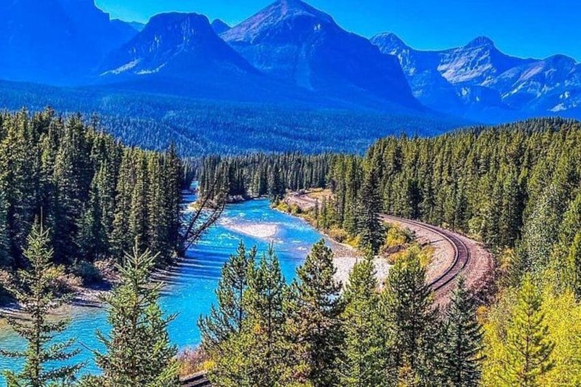 A river winding through a forest with mountains in the background. 5