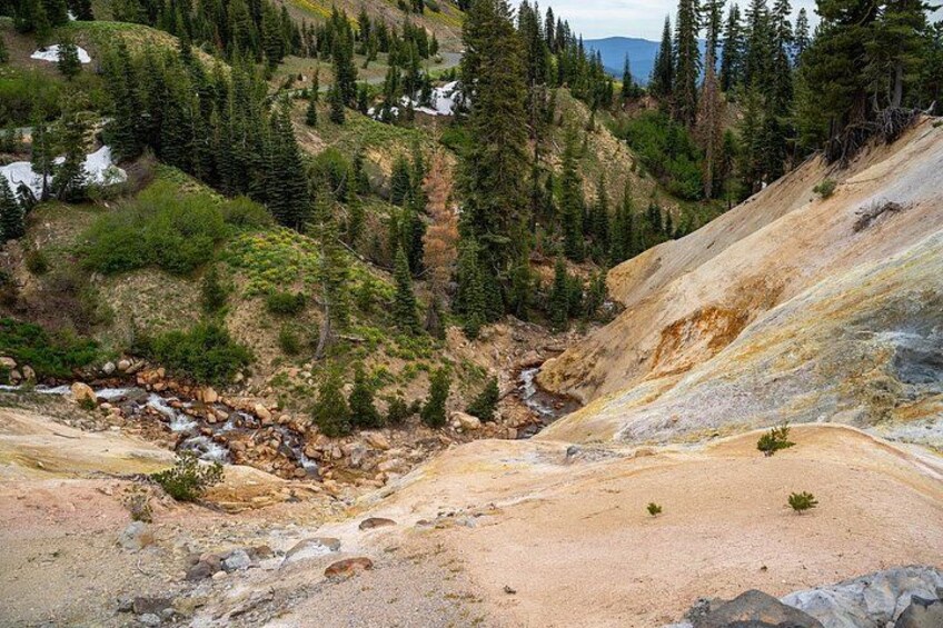 Un paysage montagneux avec un ruisseau, un terrain rocheux et une forêt dense. 1