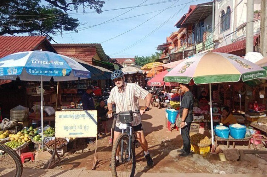 A market scene with vendors, bicycles, and produce stands. 5