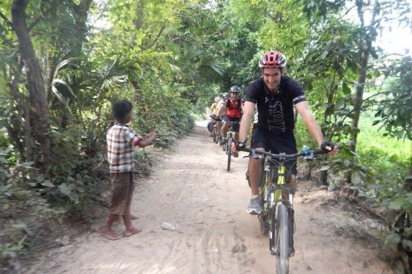 Een groep fietsers op een onverhard pad, omringd door weelderige begroeiing. 5