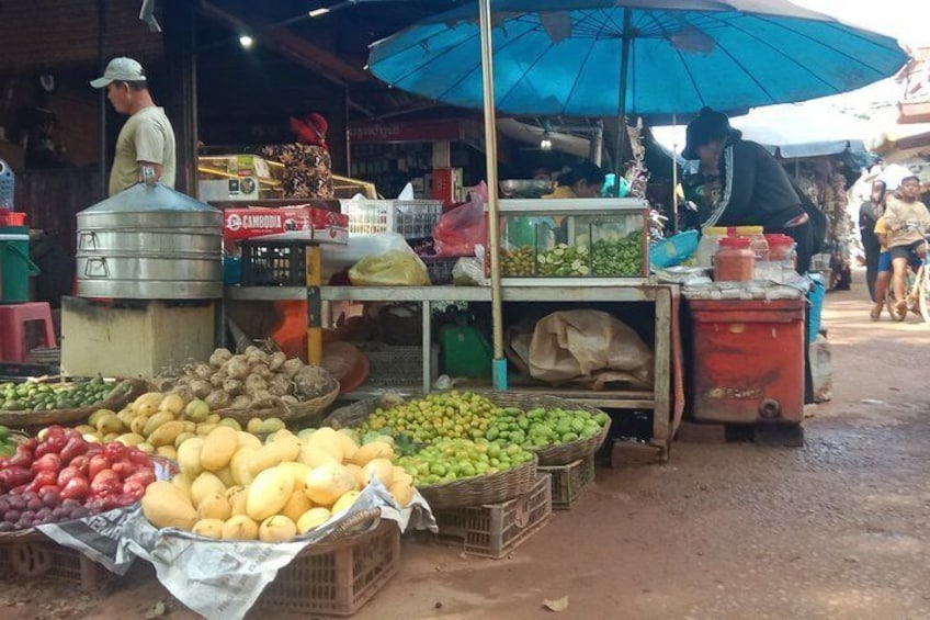 A market stall with various fruits and vegetables, a blue umbrella, and a person in the background. 3