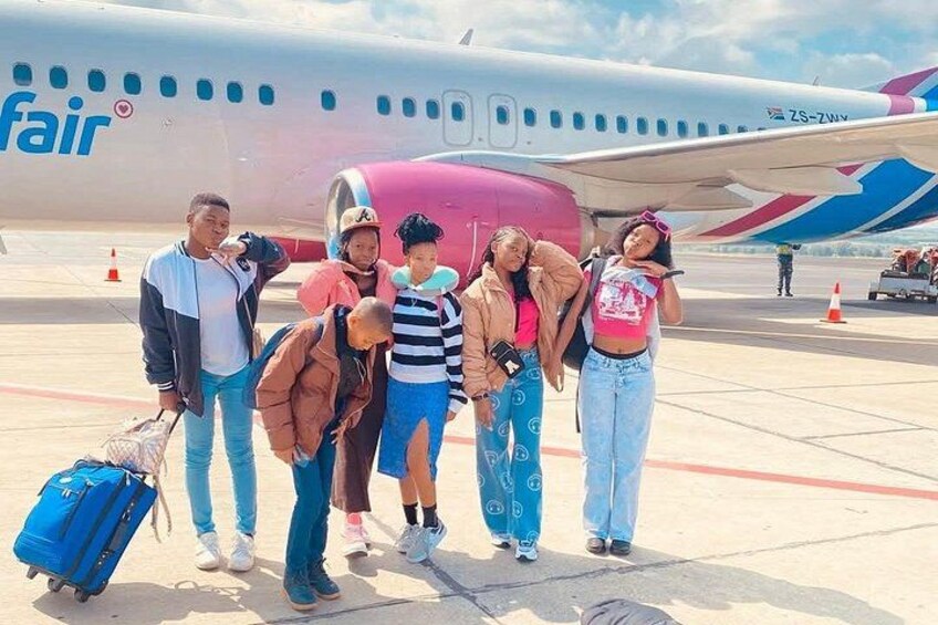 A group of people standing in front of an airplane with a 'fair' logo. 2