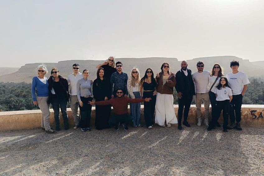 A group of people standing on a rocky outcrop with a mountainous landscape in the background. 1