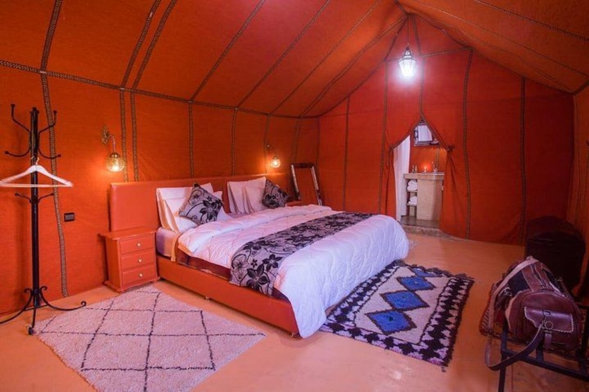 A tent with a bed, a hanging coat rack, and a small table. 3