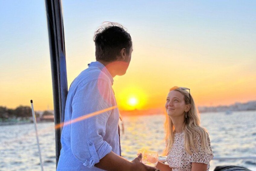 A sunset over a body of water with a boat and two people. 2