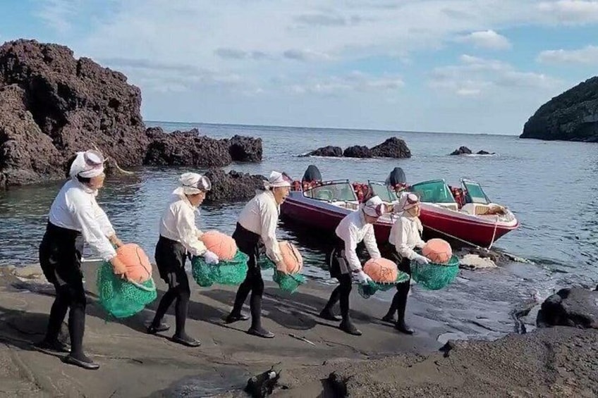 Des personnes transportent des filets près d’une côte rocheuse, avec des bateaux en arrière-plan. 5