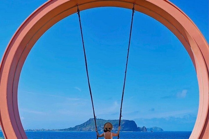 Une personne est assise sur une balançoire dont l’armature est circulaire, et elle a devant elle une étendue d’eau ainsi qu’une terre lointaine. 2