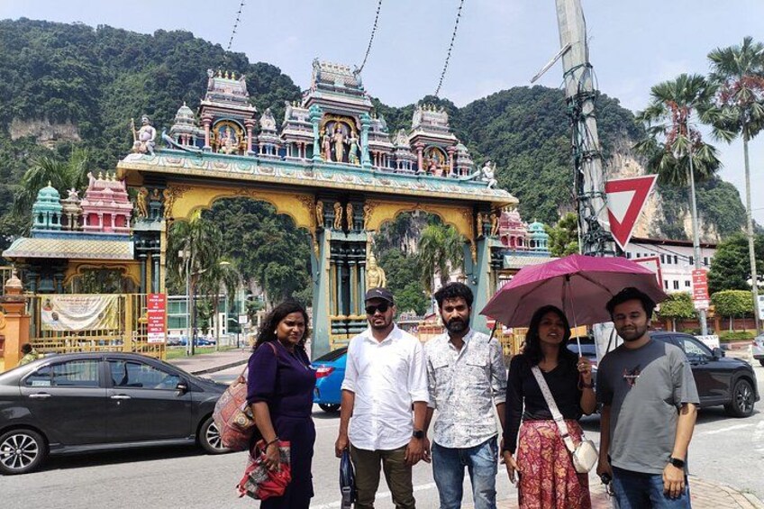 A group of people standing in front of a temple with a large archway and a mountain in the background. 4