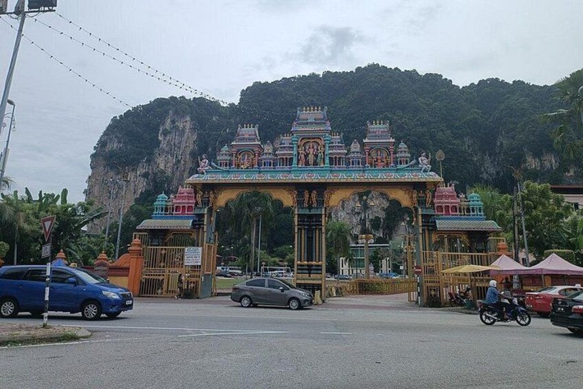 A temple with colorful architecture, a road with vehicles, and a mountainous background. 5